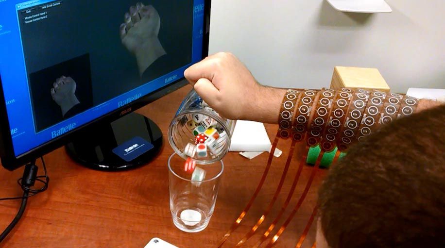 The computer screen in the upper right corner shows an avatar of Burkhart’s hand in a clenched position, which is how his hand (middle of screen) is gripping the mug. He is pouring cubes from the mug into a glass.