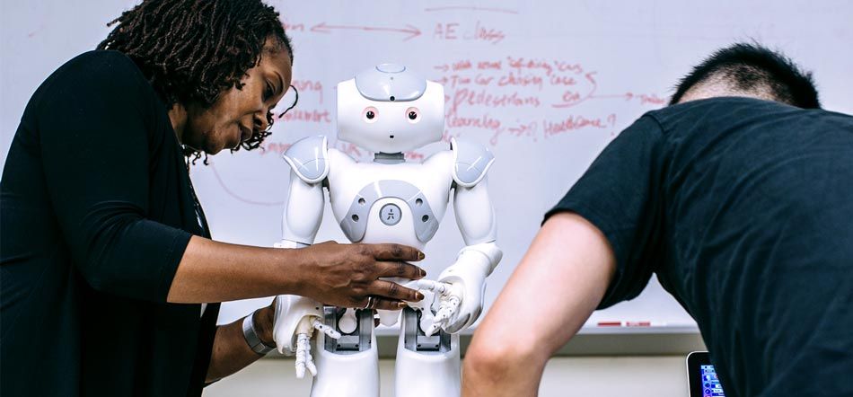 Dr. Howard holds the NAO robot while graduate student Jin Xu initializes the program on the laptop. 