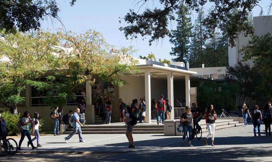 University students walking to class on a sunny day, outside of Young Hall on the UC Davis campus.