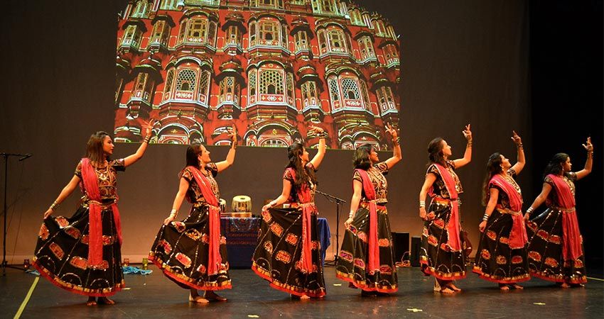 Seven female dancers in red and black traditional Indian dress